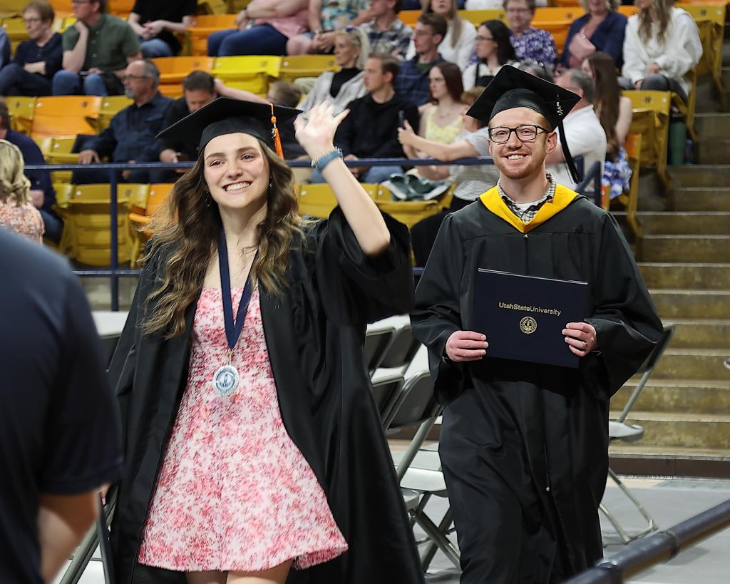 Grace and Calvin Clark wave to the crowd at Utah State University's College of Engineering Graduation Ceremony in May 2025.
